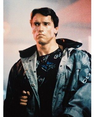 ARNOLD SCHWARZENEGGER AS THE TERMINATOR IN GREEN JACKET POINTS GUN